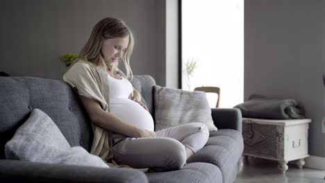 Schöne-Schwangere-Frau-Sitzt-Auf-Dem-Sofa-Und-Spricht-Mit-Dem-Baby